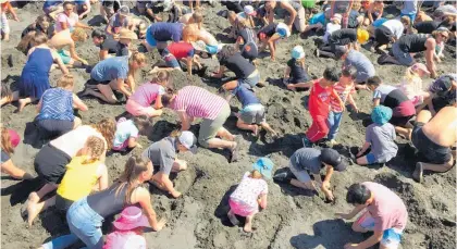  ??  ?? Sand flew as 303 adults and children dug for prizes at Kai Iwi Beach on March 3.