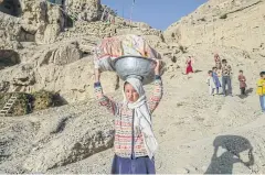  ?? AFP ?? Hazara ethnic children walk to a river from their village near the cliffs pockmarked by caves where people still live as they did centuries ago in Bamiyan.