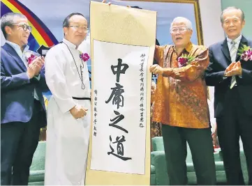  ??  ?? Tay (second left) presents a scroll with Chinese calligraph­y ‘Zhong Yong Zhi Dao’, which means moderation, as souvenir to Manyin (second right), as (from left) Dr Annuar and Tiong look on.