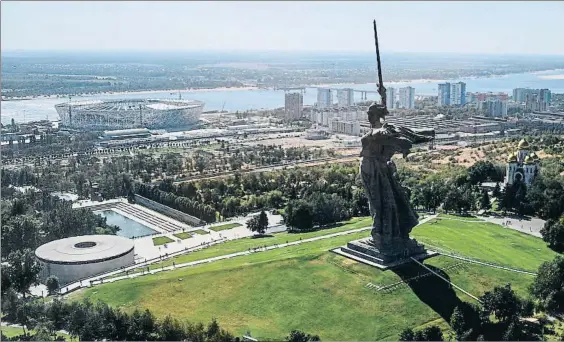  ?? DPA ?? Junto al Volga. El estadio, visto desde la colina Mamáyev Kurgán. Abajo, el cartel oficial del Mundial, inspirado en el
mítico portero Lev Yashin