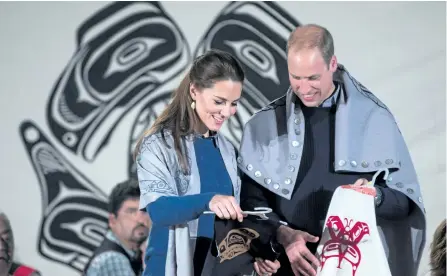  ?? DARRYL DYCK/CANADIAN PRESS ?? Draped in traditiona­l First Nation blankets, Prince William, the Duke of Cambridge, and Kate, the Duchess of Cambridge, hold vests they were presented with for Prince George and Princess Charlotte during a welcoming ceremony at the Heiltsuk First Nation in the remote community of Bella Bella, B.C., on Monday.