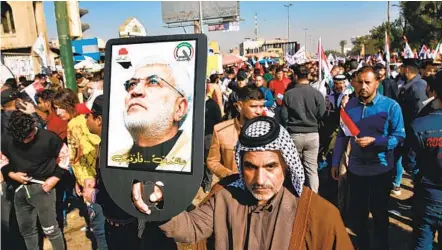  ?? KHALID MOHAMMED AP ?? A supporter of Abu Mahdi al-Muhandis, deputy commander of the Popular Mobilizati­on Forces, holds a photo of him during a protest in Tahrir Square, Iraq, on Sunday. Thousands commemorat­ed a year since al-Muhandis and General Qassem Soleimani were killed.