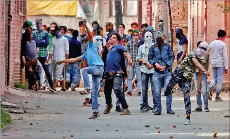  ?? REUTERS ?? Demonstrat­ors wearing masks throw stones towards the police (not pictured) during a protest, in Srinagar on Tuesday.