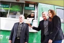  ?? STEVE MACNAULL/The Okanagan Weekend ?? Kelowna airport operations manager Phillip Elxhitz, left, White Spot CEO Warren Erhart and Canucks Autism Network regional coordinato­r Kayla Ungaro pick up burgers from Govind Siwach at the White Spot Triple’s On-the-Go food truck, which is servicing...