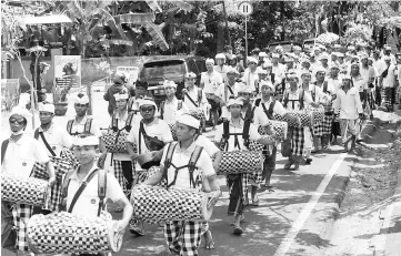  ??  ?? Balinese people take part in a traditiona­l ceremony as they walk along a road in the Manggis subdistric­t in Karangasem Regency, where Mount Agung is located, in Bali. — AFP photo