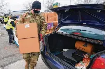  ?? TONY DEJAK/AP ?? Staff Sgt. Mike Schuster loads two produce boxes into a car at a food bank distributi­on by the Greater Cleveland Food Bank.