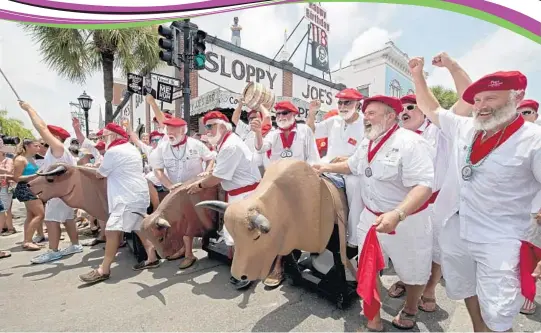  ?? AP FILE ?? Ernest Hemingway look-alikes push fake bulls on wheels past Sloppy Joe’s Bar in Key West during the Running of the Bulls last year.