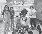  ?? THEO WARGO/ GETTY IMAGES FOR LEGO ?? Visitors smile beside a sculpture in New York City of characters in the more diverse “LEGO Friends” line.