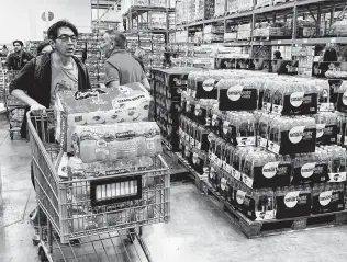  ?? Mark Ralston / AFP via Getty Images ?? People buy water, food and toilet paper at a Los Angeles store, as they begin to stockpile essentials out of fear that supplies will be affected by the spread of the coronaviru­s outbreak.