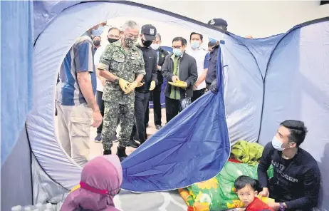  ?? — Bernama photo ?? Al-Sultan Abdullah speaks to an evacuated family at PPS Wisma Belia.