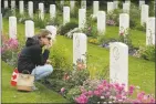  ?? Sean Gallup / Getty Images ?? Lise Belanger, 18, wipes an eye as she kneels at the gravestone of her great-uncle, Roger “Sonny” Firman, in Normandy on June 5.