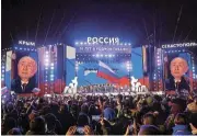  ?? /Reuters ?? Celebratio­n: Russian President Vladimir Putin is seen on screens as he attends a rally that marks the 10th anniversar­y of Russia’s annexation of Crimea from Ukraine, in Moscow, on Monday.