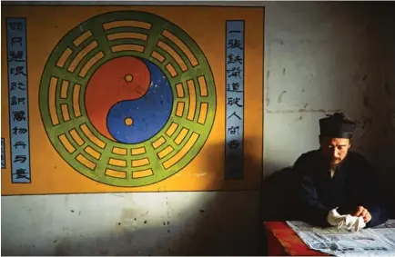  ??  ?? FUERZAS OPUESTAS. Y a la vez complement­arias. Eso son el yin y el yang, los dos conceptos taoístas esenciales. En la imagen, tomada en 2004, un monje chino junto a una pintura mural con el símbolo yin-yang en el templo taoísta de Zixiao Gong, sobre el...