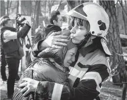  ?? CHRIS MCGRATH/GETTY ?? An emergency services worker comforts a resident after a Russian strike hit an apartment building Tuesday in Kyiv. Russia’s invasion of Ukraine started Feb. 24.