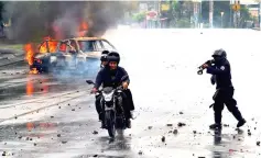  ??  ?? File photo shows a riot police officer firing his shotgun towards two men during a protest against Ortega’s government in Managua, Nicaragua. — Reuters photo