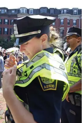  ?? STAFF PHOTO BY NANCY LANE ?? BOSTON’S FINEST: A Boston police officer tucks a flower into her safety vest while escorting marchers from Roxbury.