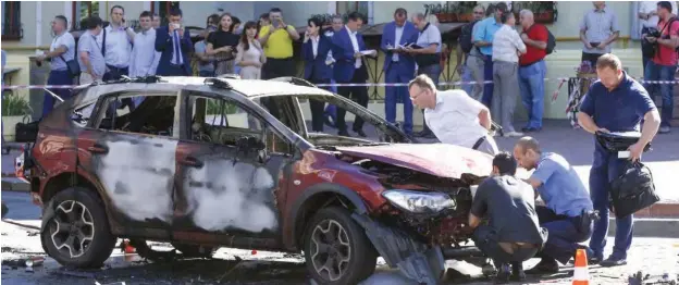  ?? PHOTOGRAPH: ?? Forensic experts examine the car in which the journalist Pavel Sheremet was killed in a bombing in Ukraine’s capital, Kiev. Sergei Chuzavkov/AP