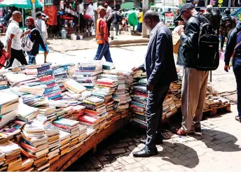  ?? ?? Pedestrian­s shop for books along the business district in Nairobi.