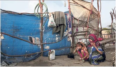  ??  ?? Awsaf, a five-year-old Yemeni girl, eats bread and drinks tea – which on many days is the only food she has – crouching next to her mother.