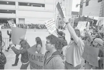  ?? Marie D. De Jesús / Houston Chronicle ?? People demonstrat­ing against President Donald Trump march toward the George R. Brown Convention Center on Saturday, passing Super Bowl Weekend guests on the other side of the sidewalk.