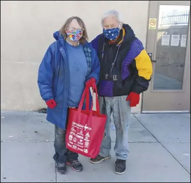  ?? JULIE DRAKE/ VALLEY PRESS ?? Lancaster couple Esther (left) and Bill Crowell picked up a bag of food and other items at Grace Resource Center on Friday for Christmas Day. About 100 prepacked meals and clothing items were distribute­d by volunteers to needy Valley families.