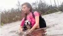 ?? TIM AYLEN/AP ?? Julia Aylen wades through water carrying her dog in Freeport, Bahamas.
