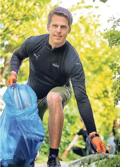  ??  ?? Sönke Schacht hebt ein Stück Plastik vom Waldboden auf. Der Vabali-Geschäftsf­ührer hat mit Kollegen auf einer fünf Kilometer langen Plogging-Runde am Elbsee allerlei Unrat aufgesamme­lt.