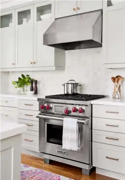  ??  ?? ABOVE After living with the kitchen’s original tiny wall oven and fold-down burners, the homeowners felt full-sized stainless steel appliances were a sensible splurge. “We were very budget-conscious during the reno,” says Karina. “The Wolf range was...