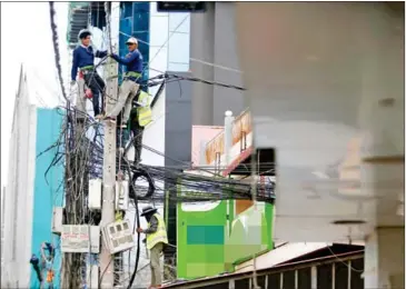  ?? HENG CHIVOAN ?? Electrical workers prepare power lines on Monivong Blvd in Chamkarmon district last August.