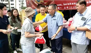  ?? — Photo by Kong Jun Liung. ?? Wee (second right) hands over the goodies a recipient, as Zaiedi (right) and others look on.