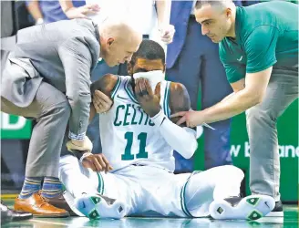  ?? ASSOCIATED PRESS ?? Team personnel assist Boston Celtics' Kyrie Irving (11) after he was injured during the first quarter of an NBA basketball game against the Charlotte Hornets in Boston. Irving took an elbow to the face and left the game.