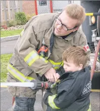  ?? MITCH MACDONALD/THE GUARDIAN ?? North River firefighte­r Joe Sawler shows three-year-old Owen Roberts of Sherwood how to use a fire hose during the fire department’s open house on Saturday. The event was part of Cornwall’s Cornfest.