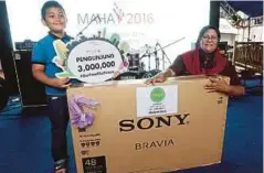  ??  ?? FARIDAH bersama anaknya memenangi televisyen 48 inci selepas diumumkan pengunjung ke-3,000,000 MAHA 2016, semalam.