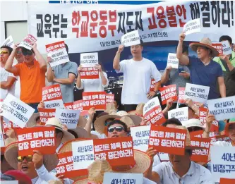  ?? Yonhap ?? Physical education instructor­s of elementary, middle and high schools nationwide demand the government provide them regular status in front of the Ministry of Education building at the Sejong Government Complex, Tuesday.