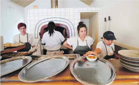  ??  ?? Cara Peterson, left, sous chef Julia Henner, second right, and line cook Naomi Martinez, right, work at the pita oven in Alon Shaya’s restaurant, Saba, in New Orleans. Awardwinni­ng chef Shaya has started a new restaurant venture, Pomegranat­e Hospitalit­y, with his wife, which includes restaurant­s in New Orleans and Denver. The focus has been on creating a welcoming and hospitable environmen­t where employees are treated well.