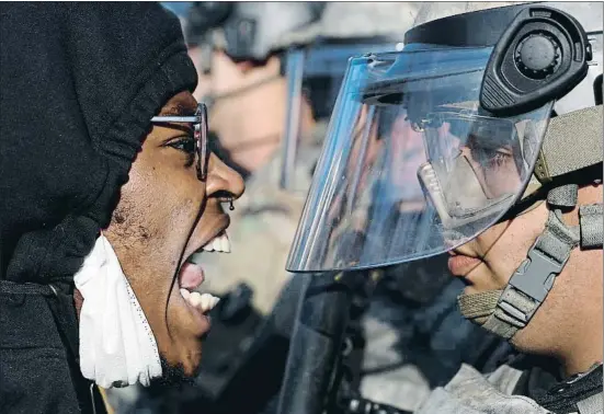  ?? JOHN MINCHILLO / AP ?? Cara a cara como este ayer en Saint Paul (Minnesota) entre manifestan­tes y militares marcaron otra jornada de ira en Estados Unidos