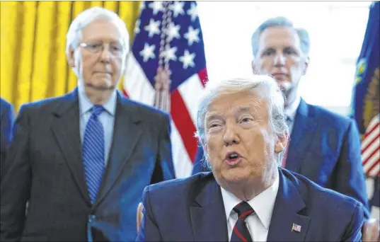  ?? Evan Vucci The Associated Press ?? President Donald Trump speaks before he signs the coronaviru­s stimulus relief package in the Oval Office at the White House on March 27 as Senate Majority Leader Mitch McConnell, left, and House Minority Leader Kevin McCarthy listen.