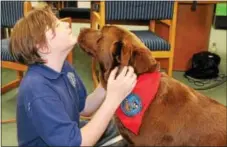  ?? MICHILEA PATTERSON — DIGITAL FIRST MEDIA ?? Coventry Christian Schools student Maggie Thompson, 12, gets her faced licked by Kahlua, a pet therapy dog. The dog visited the school last month as part of mental health awareness education activities.