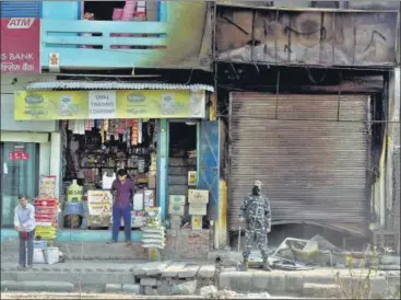  ?? SANCHIT KHANNA/HT PHOTO ?? A security personnel stands outside a burnt shop in a riot-affected at Chand Bagh, on Monday. As per an interim report by district n administra­tion, as many as 122 houses were burnt during violence.