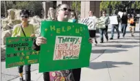  ?? Bizuayehu Tesfaye ?? Gabriela Waits, left, a therapist, and Carie Olsen, front, join psychologi­sts as they protest a new Medicaid rule before a hearing Tuesday at the Grant Sawyer State Office Building.Las Vegas Review-journal