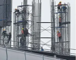  ?? PANUMAS SANGUANWON­G ?? Workers build supports for a condominiu­m in Bangkok. Large structures will be subject to the new energy code when it takes effect this year.