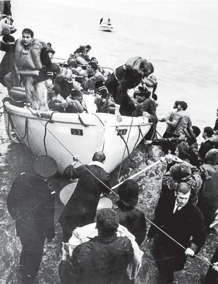  ??  ?? Lifeboat No 2 from the Wahine is brought ashore at Seatoun Beach. Engineer Phil Bennett, who skippered the lifeboat, is top left.