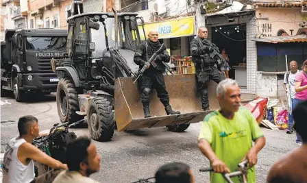  ?? SILVIA IZQUIERDO AP ?? Police officers ride in a bulldozer they use to clear street barricades during an operation against organized crime in the Mare complex of favelas in Rio de Janeiro on Monday. Forces targeted three neighborho­ods controlled by the Red Command drug traffickin­g group.