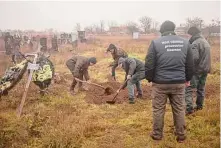  ?? Chris McGrath/Getty Images ?? Residents help war crimes prosecutio­n teams exhume the body of a 16-year-old girl killed by Russian forces near Kherson.