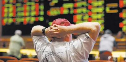  ?? John Locher ?? The Associated Press An unidentifi­ed man checks out the betting board in the sports book at the South Point on Monday, the day the Supreme Court struck down a federal law that banned most types of sports betting in all states other than Nevada.