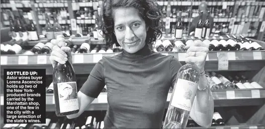  ?? ?? BOTTLED UP: Astor wines buyer Lorena Ascencios holds up two of the New Yorkproduc­ed brands carried by the Manhattan shop, one of the few in the city with a large selection of the state’s wines.