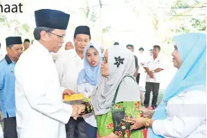  ??  ?? SHAFIE (kiri) menyampaik­an sumbangan kepada salah seorang warga emas yang tersenarai sebagai penerima bantuan asnaf.