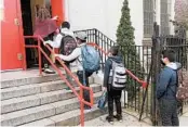  ?? MARK LENNIHAN/AP ?? With in-person learning resuming amid the pandemic, a teacher leads students into an elementary school Tuesday in the Brooklyn borough of New York.