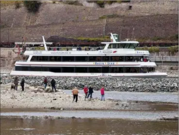  ?? MICHAEL PROBST — THE ASSOCIATED PRESS ?? People stand on sandbank Oct. 24 in the river Rhine near Bingen, Germany, during historical­ly low water levels. A hot, dry summer has left German waterways at record low levels, causing chaos for the inland shipping industry, environmen­tal damage and billions of euros of losses — a scenario that experts warn could portend things to come as global temperatur­es rise.