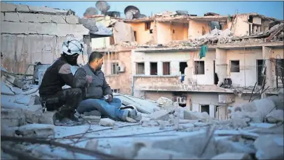  ?? [GRASSHOPPE­R FILM] ?? Two members of the White Helmets, including Khaled, right, watch as other Syrian rescue workers search a shattered building for survivors in “Last Men in Aleppo”